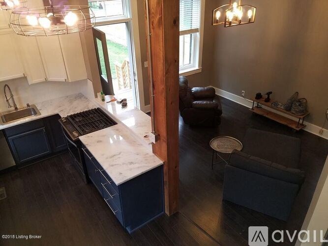 A kitchen with a marble countertop and a black stove top oven.