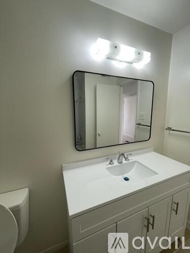 A bathroom with a sink, toilet and mirror.