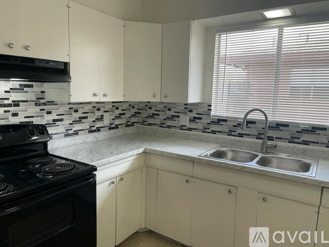 A kitchen with a black stove top oven and a black and white backsplash.