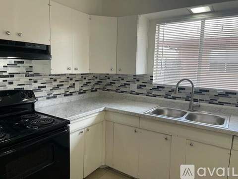 A kitchen with a black stove top oven and a black and white backsplash.