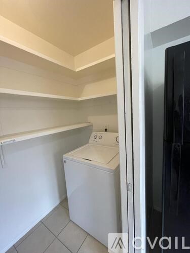 A white washing machine sits in a small laundry room.