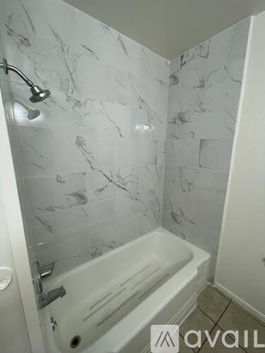 A white bathtub with a shower head attached to the wall.