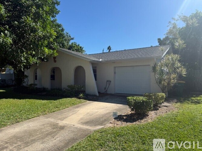 A white house with a brown roof and a driveway in front.