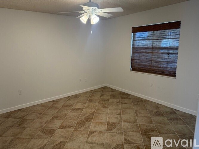 A room with a ceiling fan and a window with blinds.