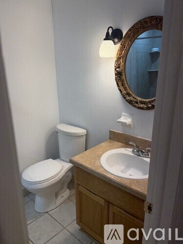 A bathroom with a toilet, sink and mirror.