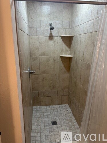 A shower area with a tiled floor and walls.