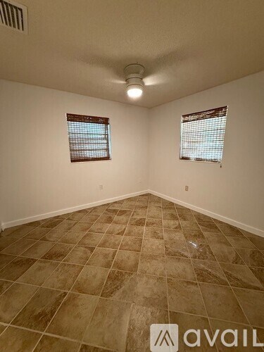 A room with tile flooring and two windows.