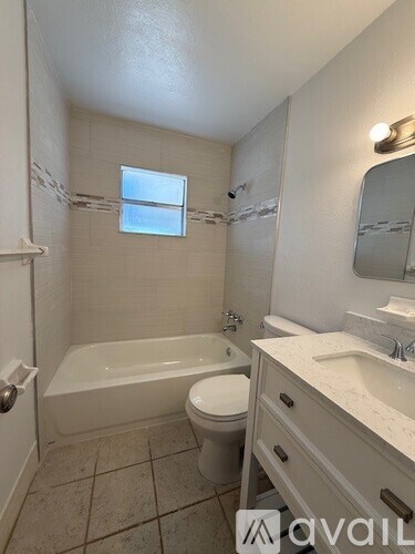 A bathroom with a tub, toilet, and sink.