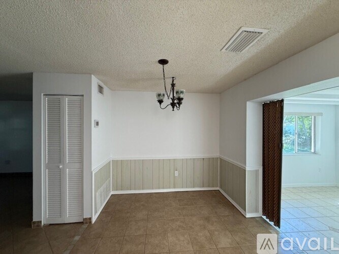 A room with a chandelier and a window with curtains.