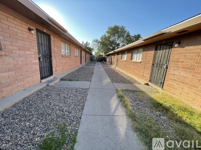 A long, narrow walkway separates a row of brick buildings.