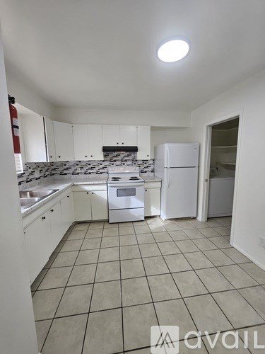 A kitchen with white appliances and tiled floors.