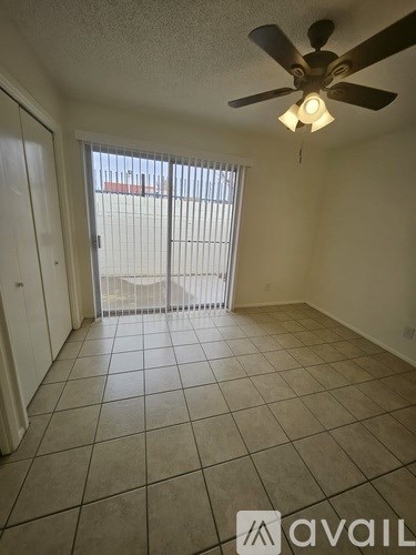 A room with a ceiling fan and sliding glass doors.