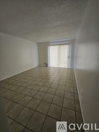 A room with tiled flooring and a window with blinds.