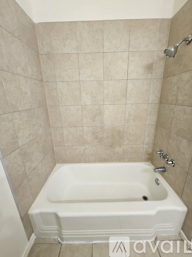 A white bathtub in a tiled bathroom.