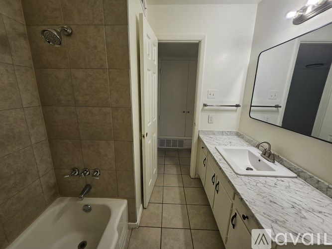 A bathroom with a tub, sink, and mirror.