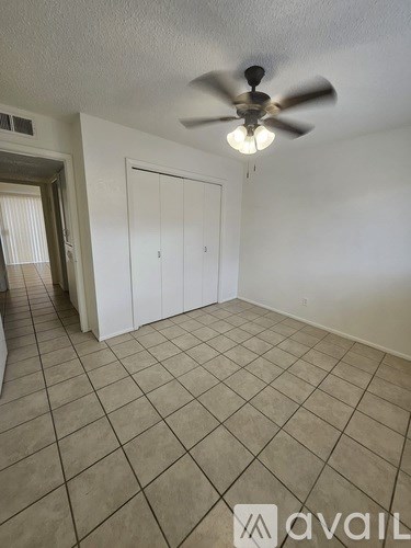 A room with a ceiling fan and tiled flooring.