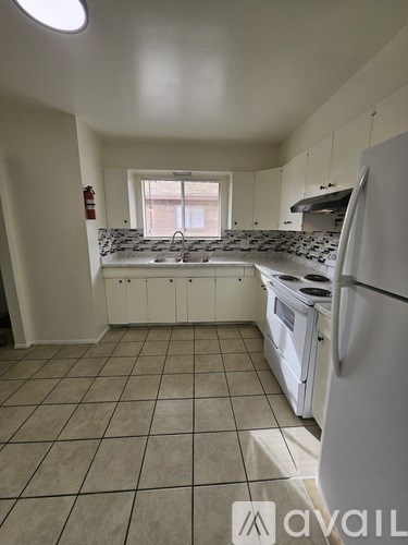 A kitchen with white appliances and tiled floors.