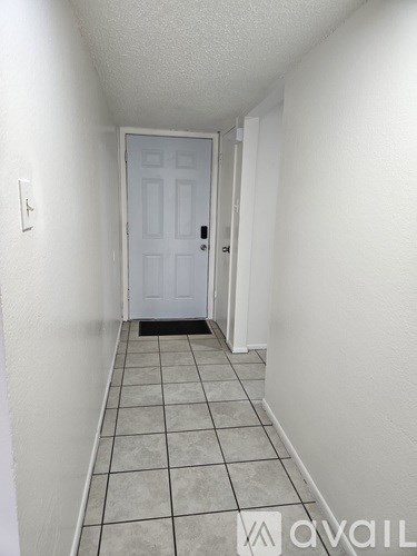 A hallway with a white door and tiled floor.