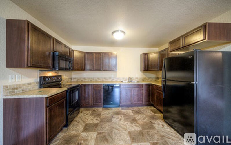 A kitchen with brown cabinets and a black refrigerator.