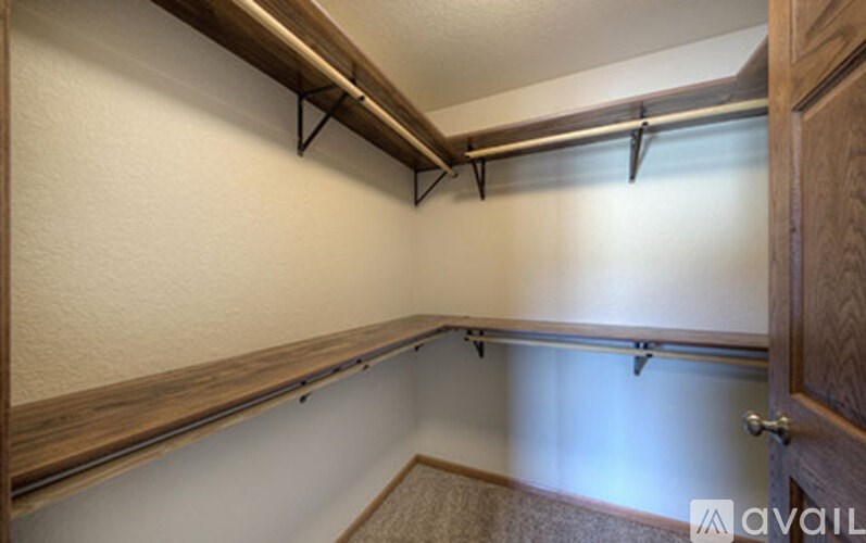 A room with a white wall and a brown shelf.