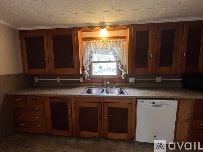 A kitchen with wooden cabinets and a white dishwasher.