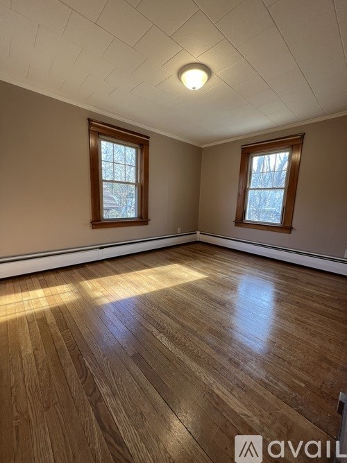 A room with wooden floors and two windows.