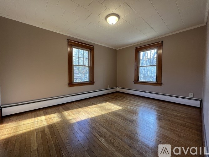 A room with wooden floors and two windows.