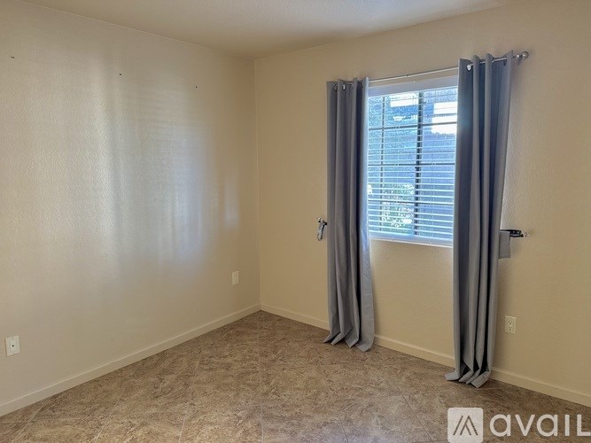 A room with a window covered by grey curtains.