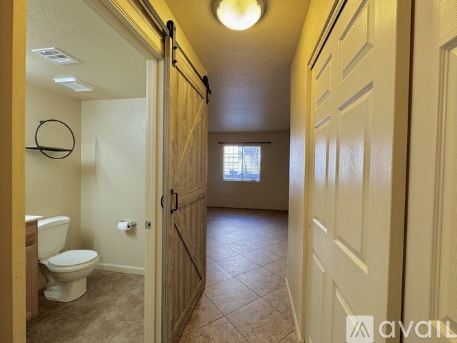A bathroom with a toilet, sink, and a door leading to another room.