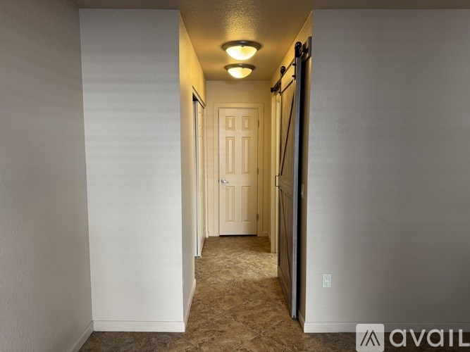 A hallway with a carpeted floor and a door at the end.
