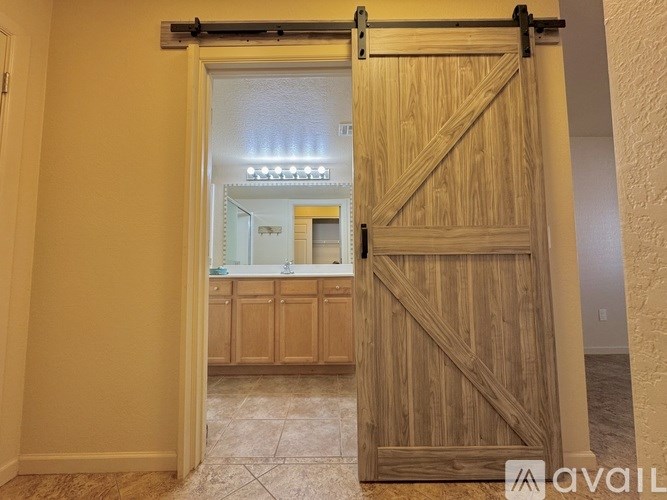 A room with a wooden door and a kitchen in the background.