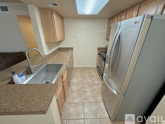 A kitchen with a stainless steel refrigerator and a granite countertop.