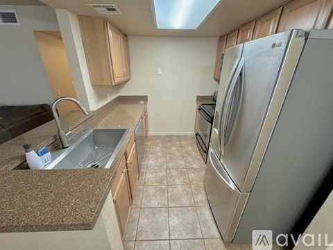 A kitchen with a stainless steel refrigerator and a granite countertop.
