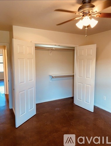 A room with a ceiling fan and a doorway leading to another room.