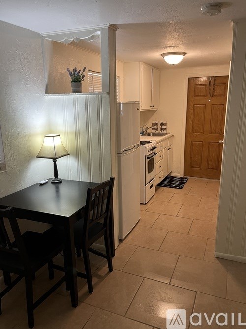A kitchen with a table and chairs in the foreground and a refrigerator in the background.