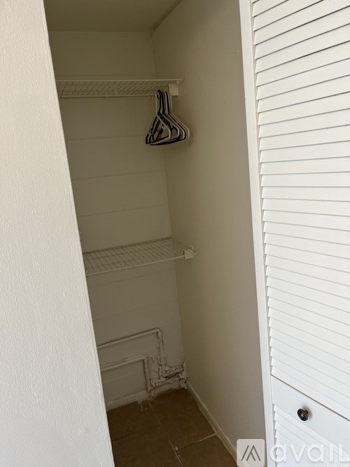 A white closet with a hanger on the shelf.