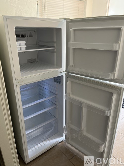 A white refrigerator with the door open and shelves visible.