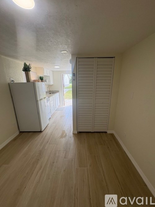 A kitchen with a table and chairs in the foreground and a refrigerator in the background.