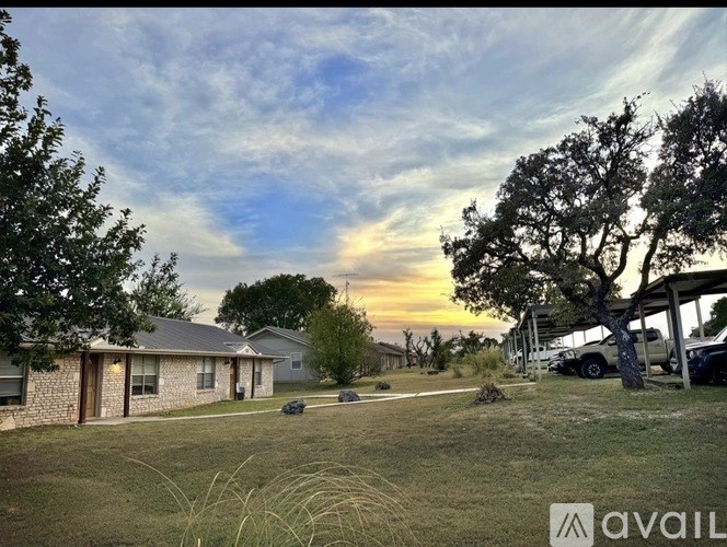 A house with a carport and a tree in front of it.