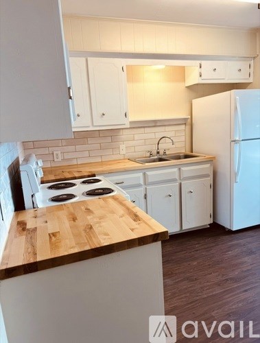 A kitchen with white cabinets and a wooden countertop.