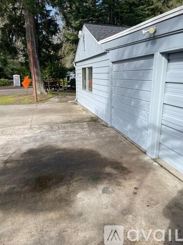A grey building with a sign in front of it.
