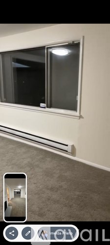 A window with a white frame and a black screen is in a room with a grey carpet.