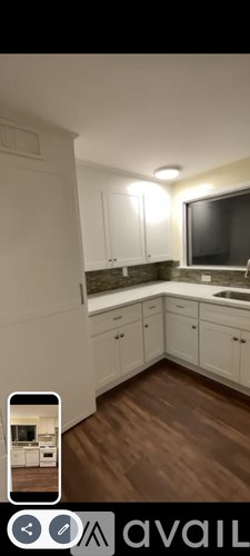 A kitchen with white cabinets and a wooden floor.