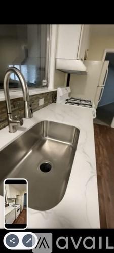 A modern kitchen with a stainless steel sink and a white countertop.