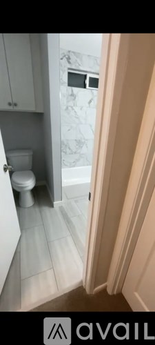 A bathroom with a toilet and a marble wall.