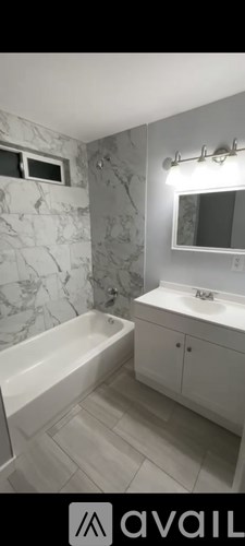 A bathroom with a marble wall and a white bathtub.