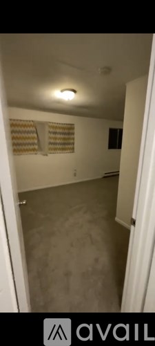 A room with a carpeted floor and a window with blinds.