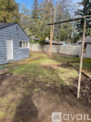 A backyard with a wooden swing set and a blue house in the background.