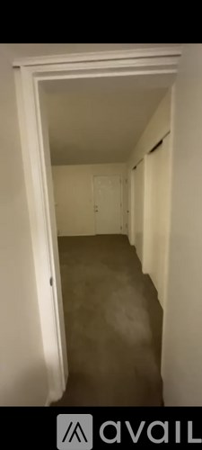 A hallway with a white door and a white wall.