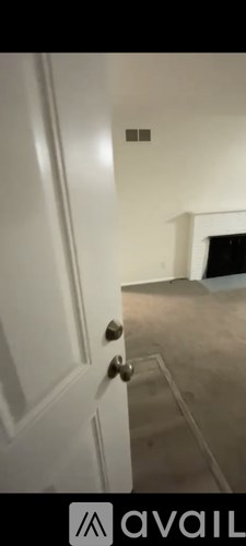 A white door with a silver handle is in the foreground of the image.